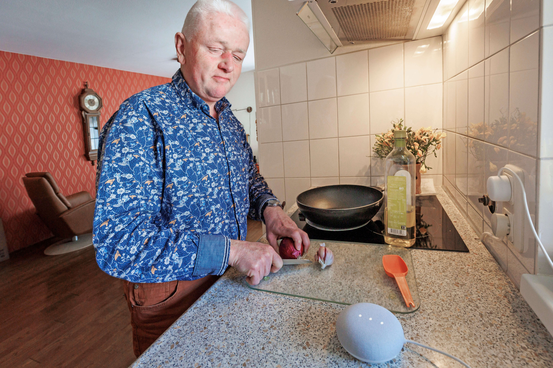 Wim Pierik in zijn keuken aan het koken met op de voorgrond een Google nest mini speaker